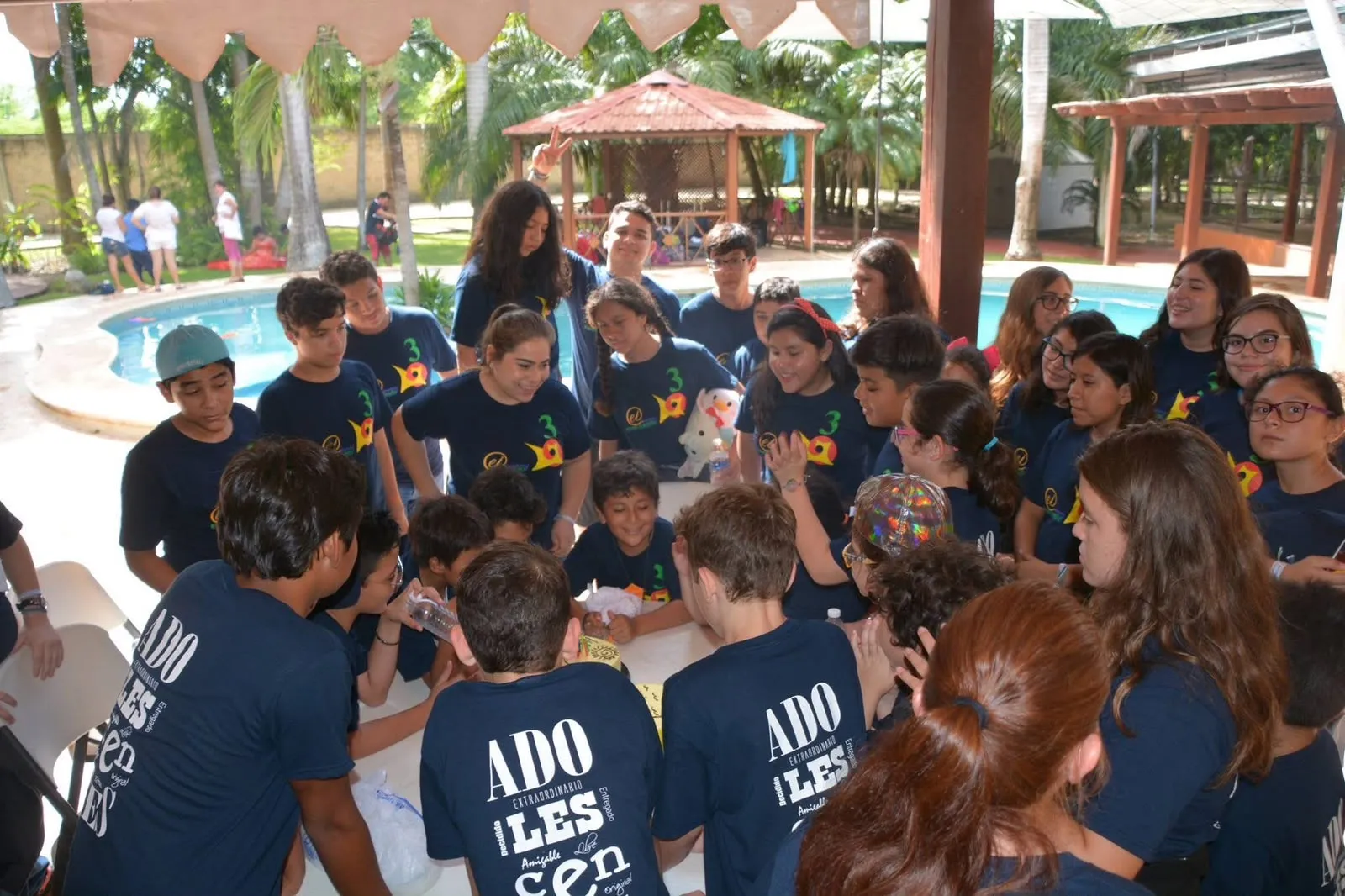 Adolescentes de una generación del programa reunidos alrededor de una mesa junto a la alberca