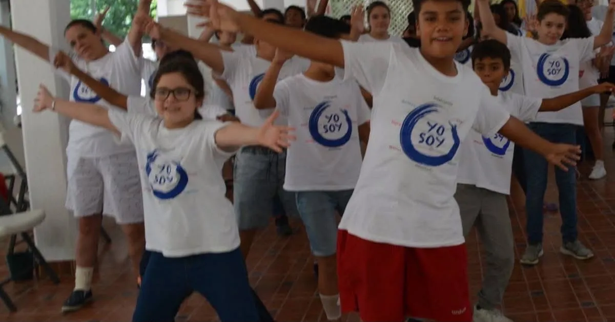 Participantes con los brazos abiertos durante una dinámica del programa